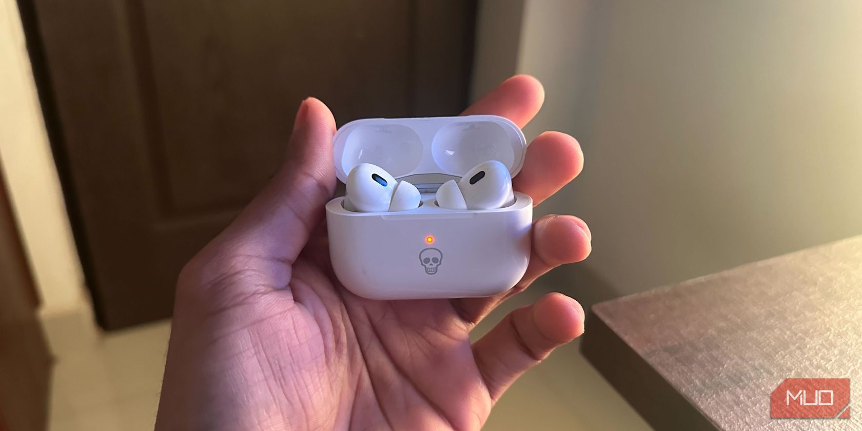 A guy holding AirPods Pro in charging case showing orange light